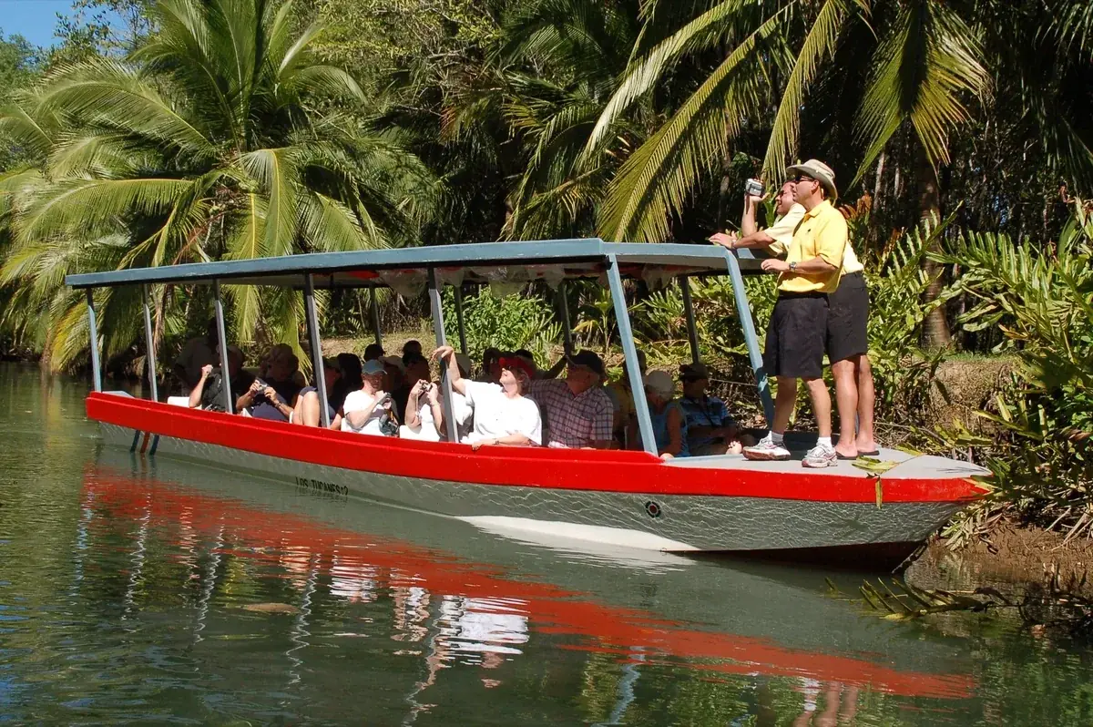 Guests seated under the roof of a red tour boat watching wildlife in the Isla Damas mangroves near Quepos, Costa Rica