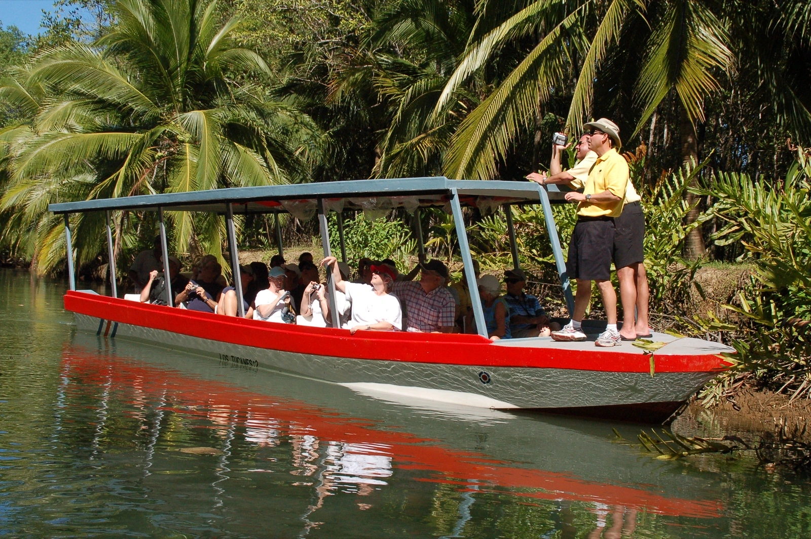 Guests photographing wildlife from a covered boat with a naturalist guide in the Isla Damas mangrove channels
